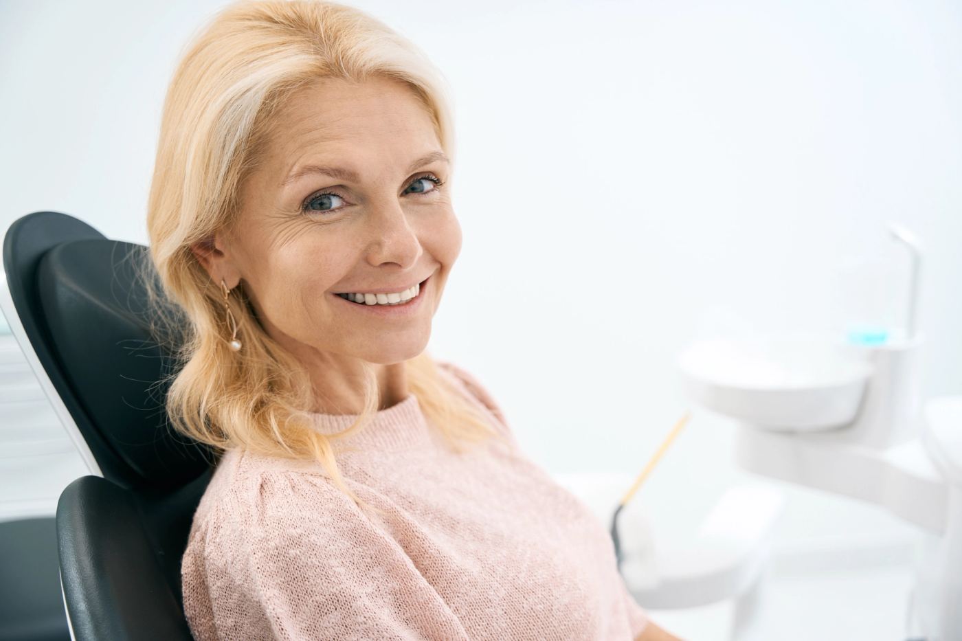 A smiling blonde woman in a dental chair.